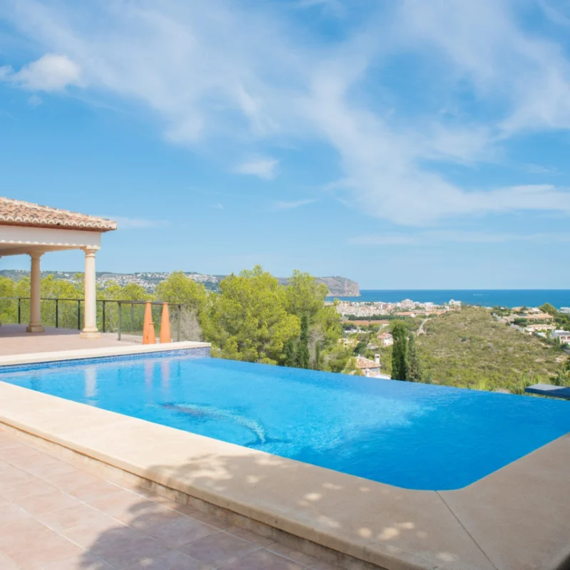Infinity-Pool mit Fliesenterrasse und klassischer Säulenveranda. Bietet einen Panoramablick auf das Mittelmeer und die Küste von Jávea.