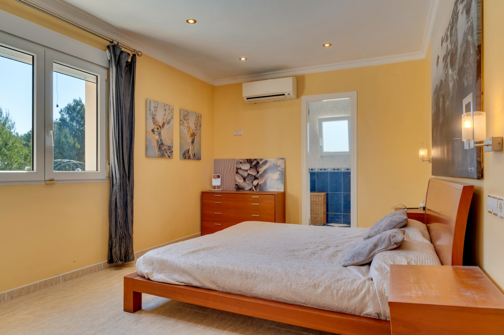 Helles Schlafzimmer mit Klimaanlage, Fliesenboden und direktem Zugang zum En-Suite-Badezimmer. PVC-Fenster ermöglichen einen weiten Blick in die umliegende Natur.
