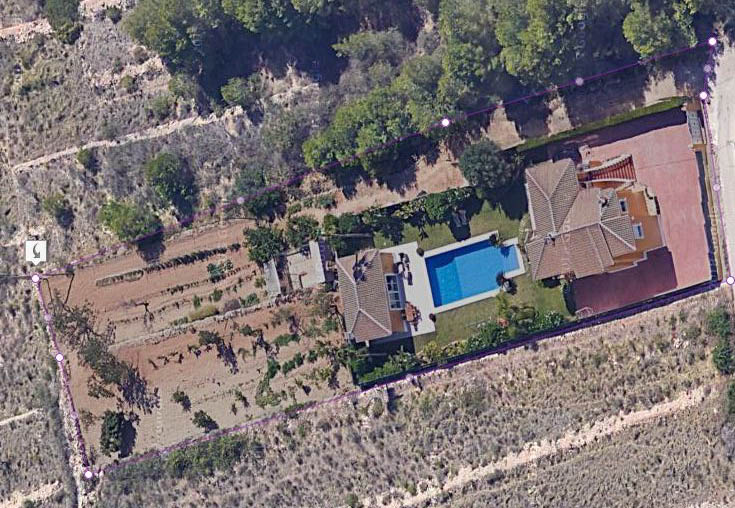 Luftaufnahme des abgegrenzten Grundstücks mit der Hauptvilla, dem 15x6 m großen Pool, dem Grillhaus und einer großen flachen landwirtschaftlichen Fläche.