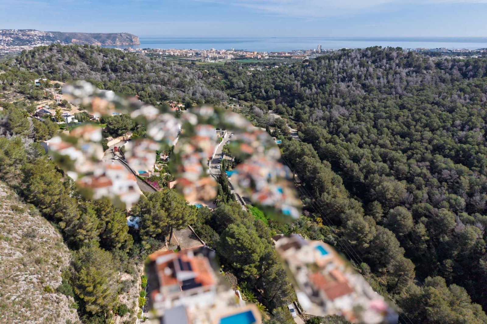 Panorama-Luftaufnahme von Sol de Este über dichte Pinienwälder hinweg mit Blick auf die Küstenstadt Jávea und das weite Mittelmeer.