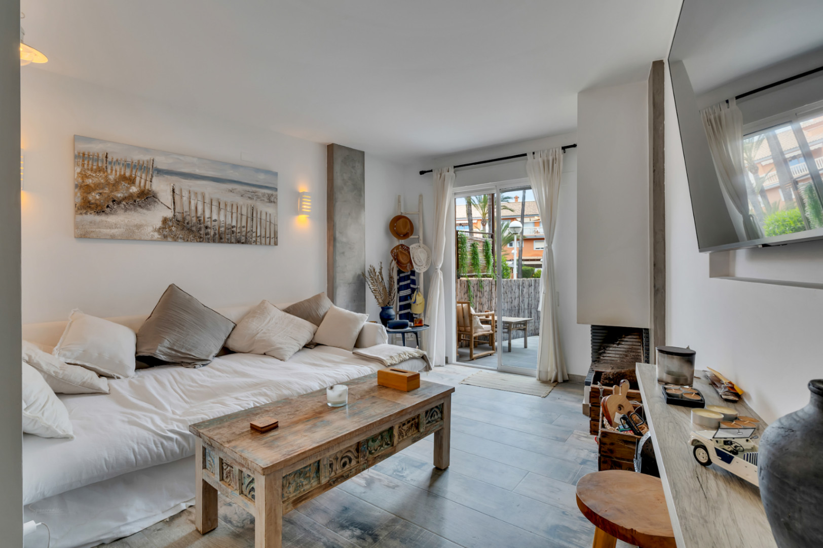 Helles Wohnzimmer mit Schlafsofa, Couchtisch aus geschnitztem Holz und Zugang zur Terrasse.