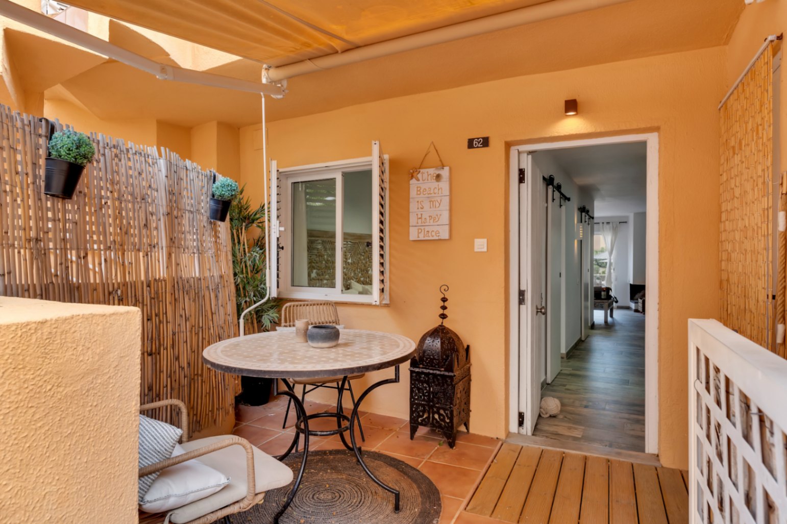 Private Terrasse mit Fliesenboden, rundem Tisch mit Korbstühlen und Dekoration im Bohème-Stil.