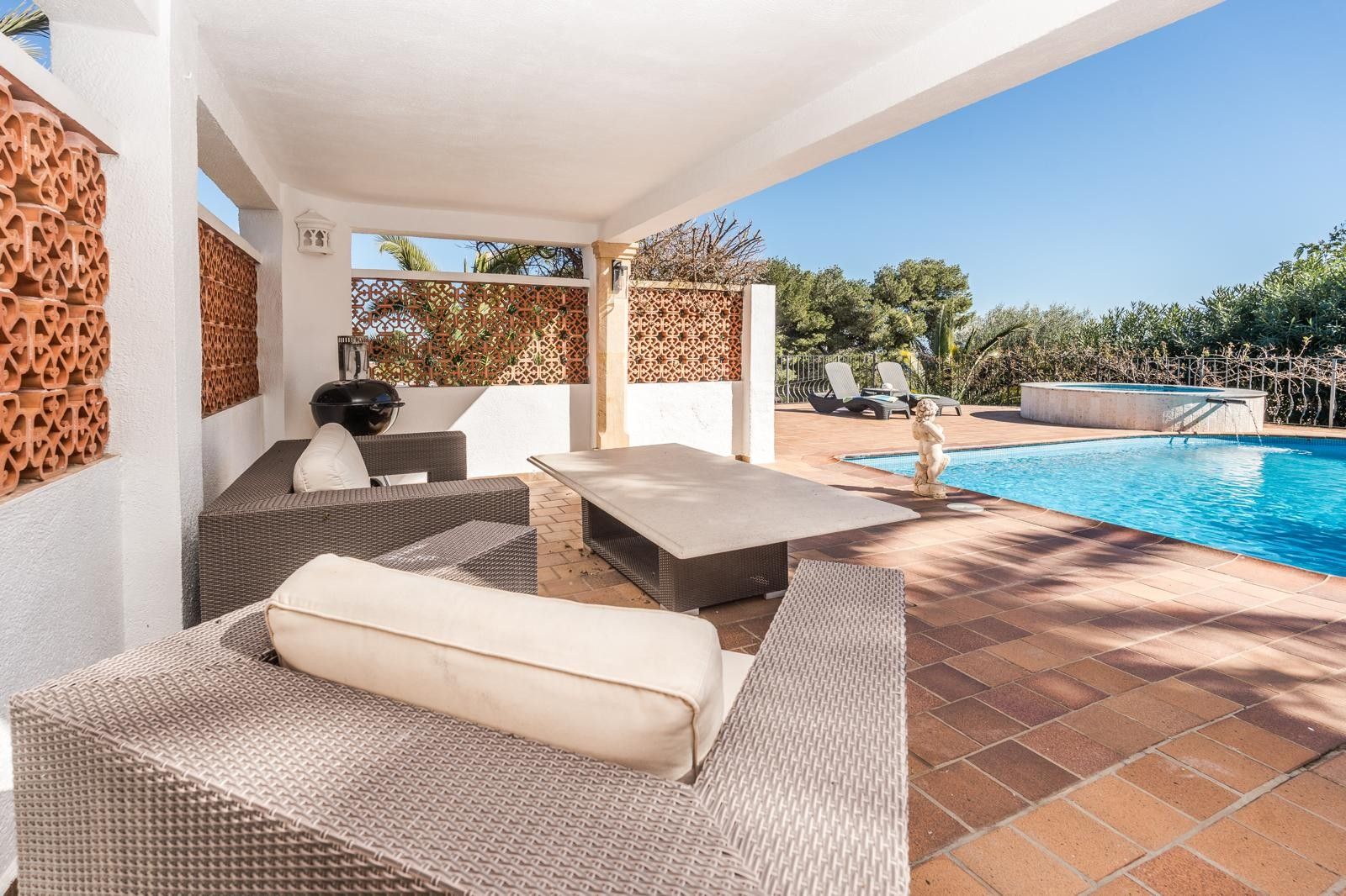 Überdachte Terrasse mit grauen Rattansitzmöbeln und Steintisch, direkt am renovierten Pool und dem runden Außen-Jacuzzi gelegen.