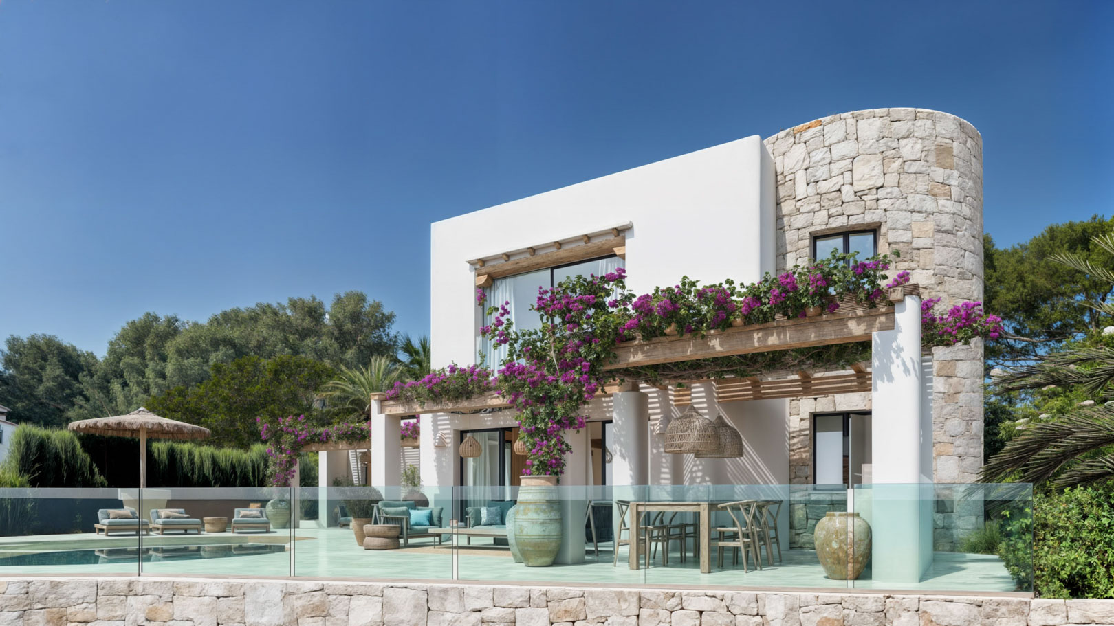 Außenansicht der Ibiza-Villa mit blumiger Pergola, Pool und Steinfassade.
