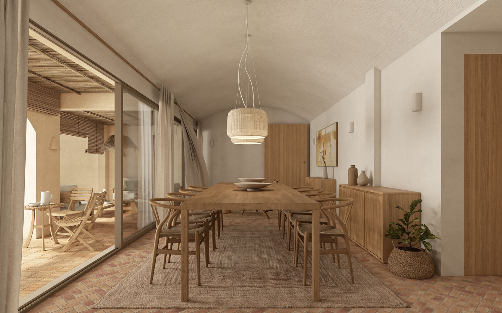 Essbereich mit Deckengewölbe, Holztisch und Wishbone-Stühlen auf Terrakottaboden. Große Glasschiebetüren verbinden den Raum mit einer überdachten Terrasse im mediterranen Stil.