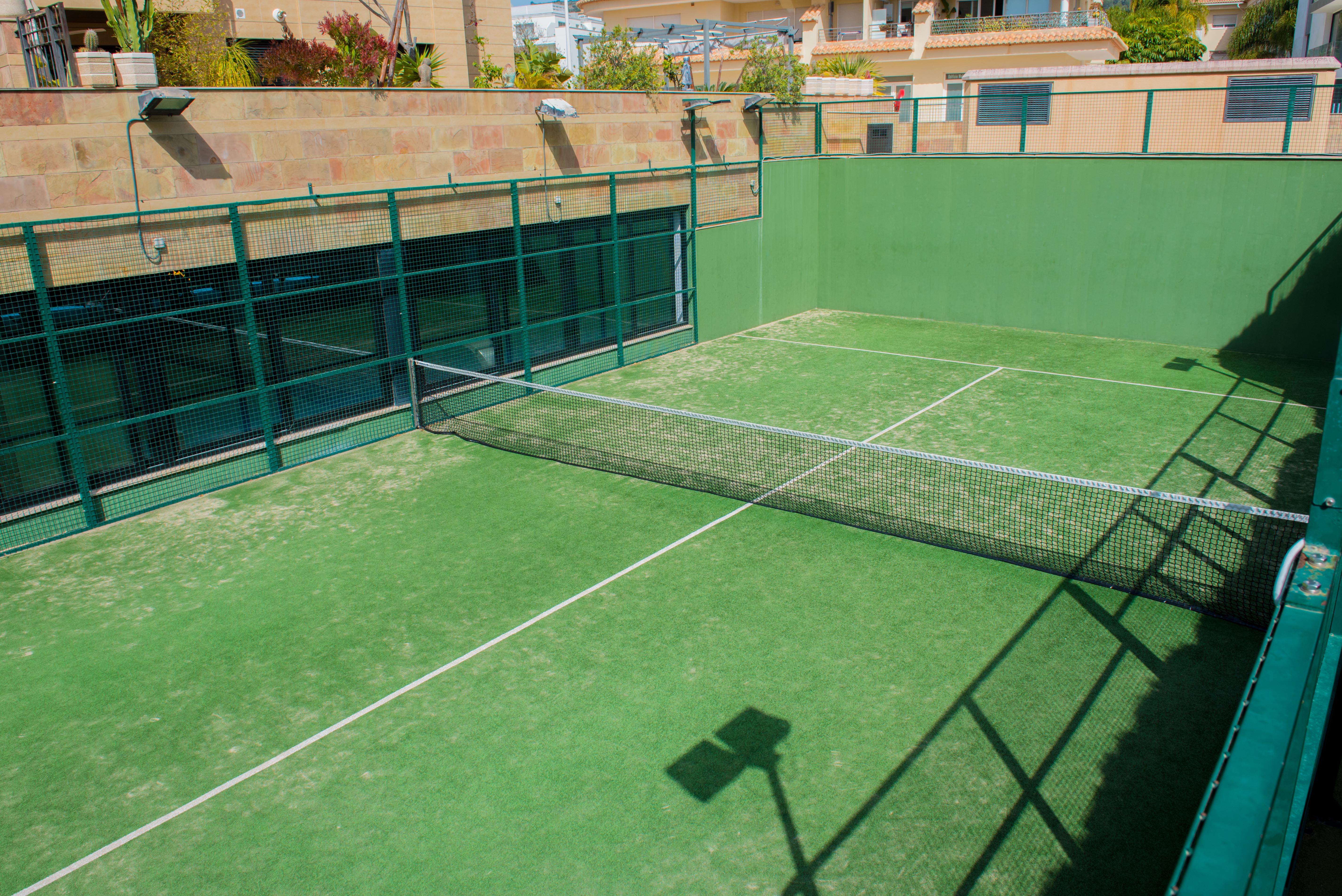 Privater Paddle-Tennisplatz mit grünem Kunstrasen und Metallumzäunung in den Gemeinschaftsbereichen der Wohnanlage in Jávea.