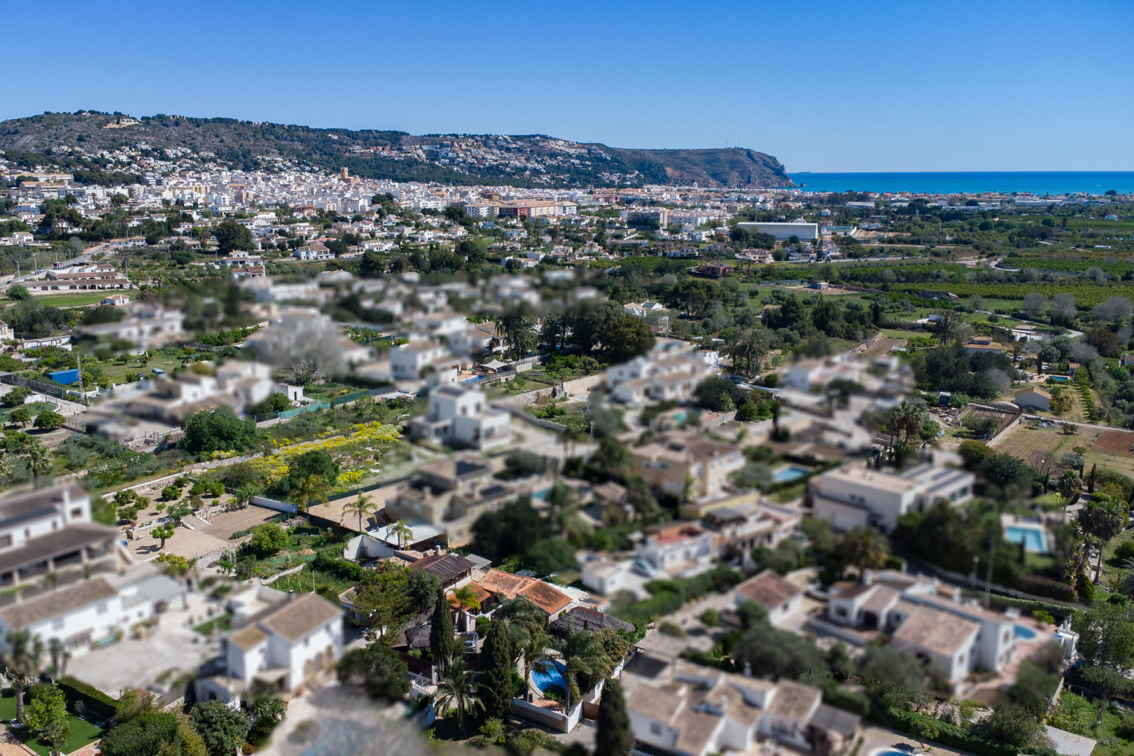 Luftaufnahme des Wohngebiets in Jávea, die die Nähe zum Stadtzentrum, zur Mittelmeerküste und zu den umliegenden Hügeln verdeutlicht.