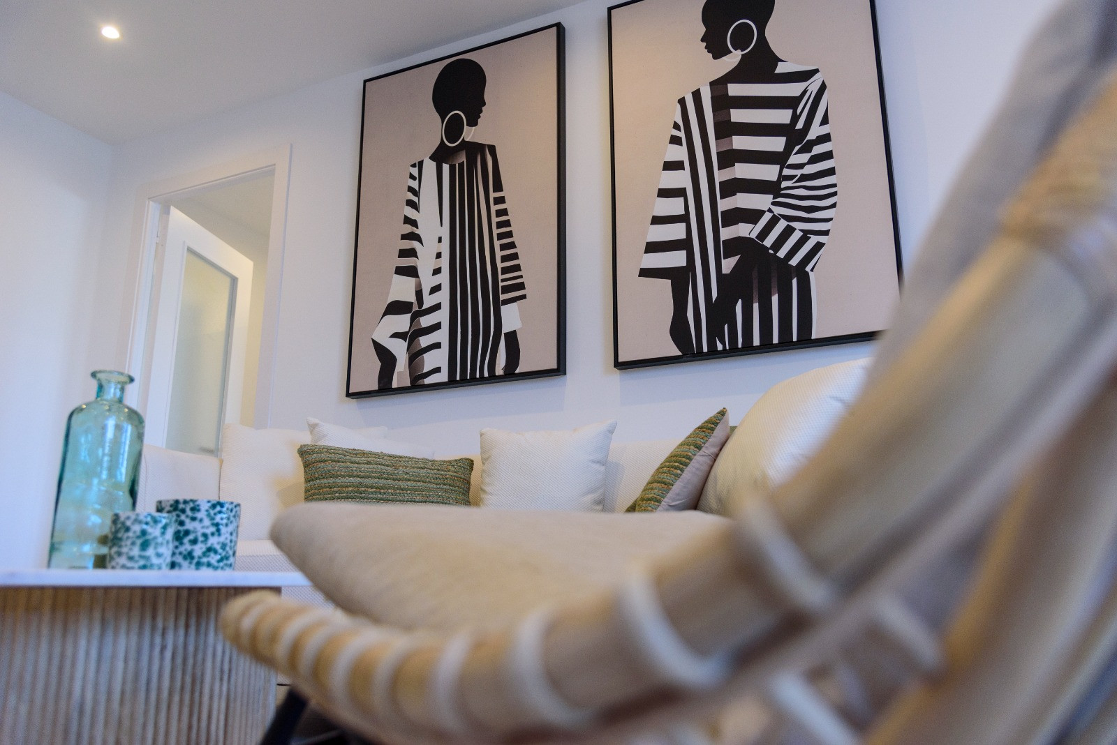 Moderner Wohnbereich mit weißen Sofas, strukturierten Kissen und minimalistischer Kunst. Ein geriffelter Couchtisch aus Holz unterstreicht das zeitgemäße Design.