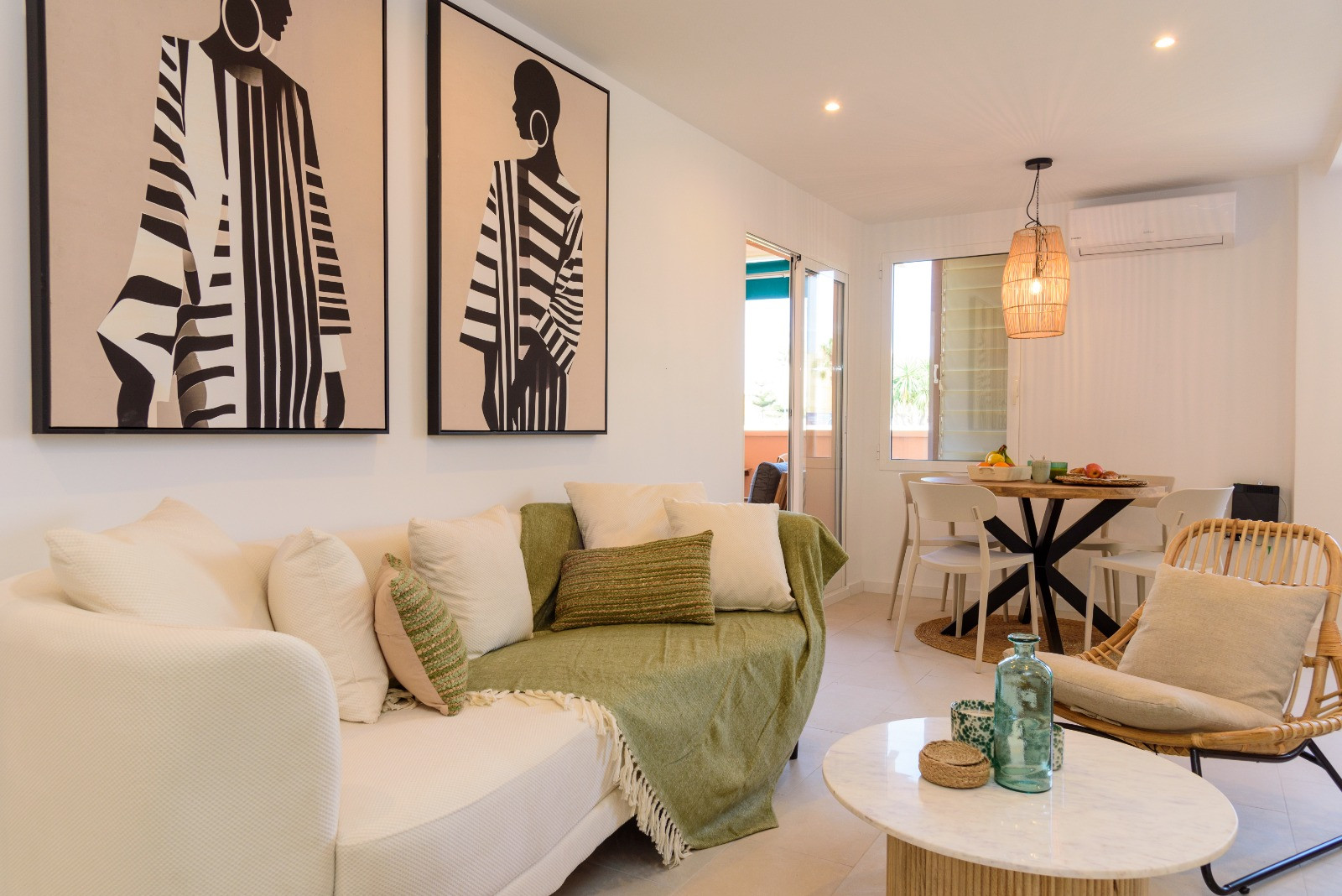 Zeitgenössischer Wohn- und Essbereich mit neutralem Sofa, moderner Kunst und rundem Esstisch. Ein direkter Zugang zur Terrasse sorgt für reichlich natürliches Licht.
