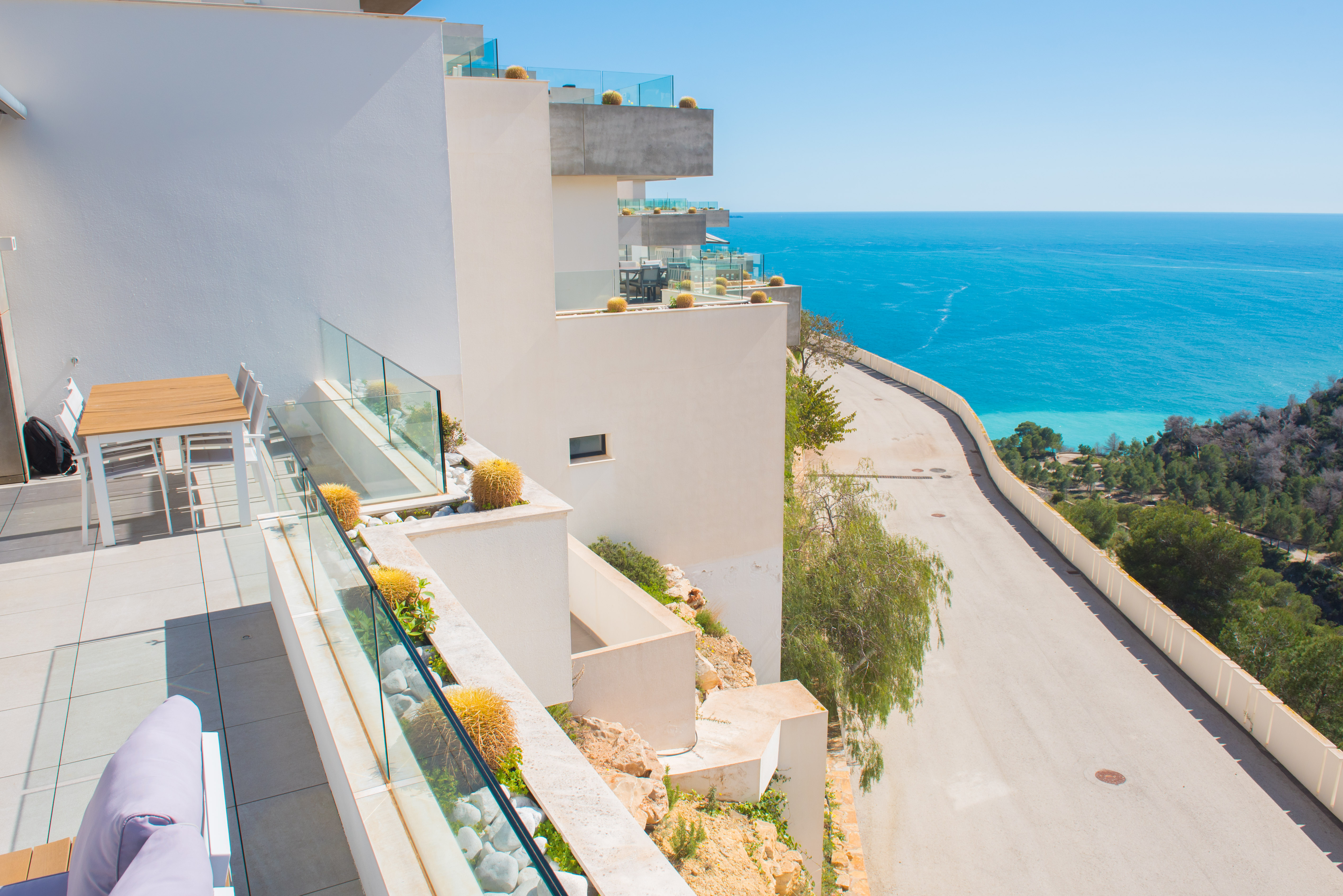 Private Terrasse mit Glasgeländern und integrierten Pflanzgefäßen mit Kakteen, mit Blick auf das Mittelmeer und die Küste von Benitachell.