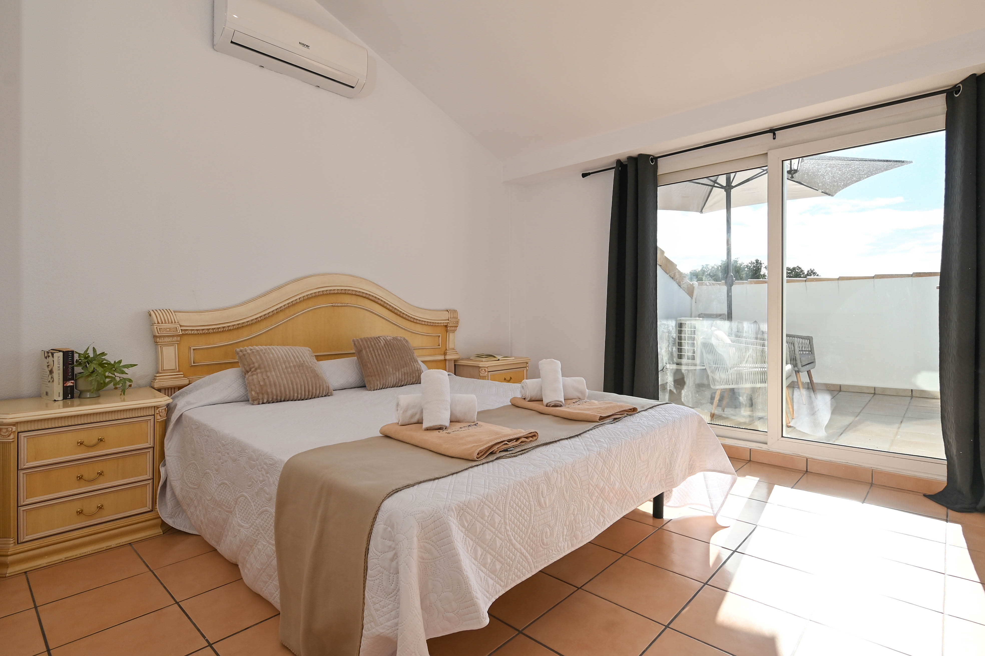 Schlafzimmer mit Dachschrägen, Klimaanlage und direktem Terrassenzugang. Ausgestattet mit Terrakottaboden und klassischen Holzmöbeln.