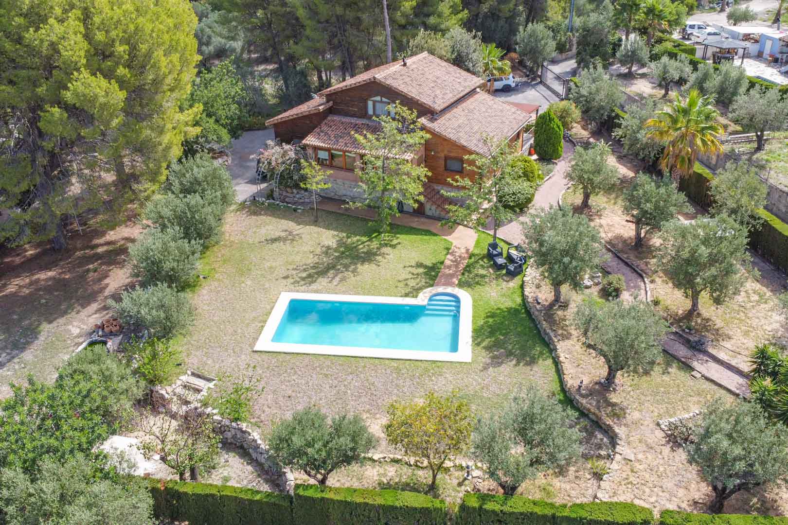 Luftaufnahme der Villa aus finnischer Kiefer und Naturstein mit privatem Pool, umgeben von Olivenbäumen und mediterranen Gärten in Orba, Alicante.