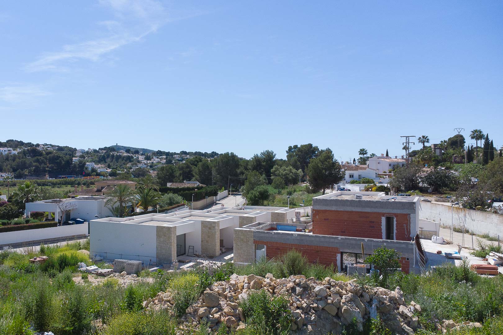 Außenansicht der im Bau befindlichen Residenz mit Natursteinakzenten und moderner Architektur in der grünen Umgebung von Moraira.