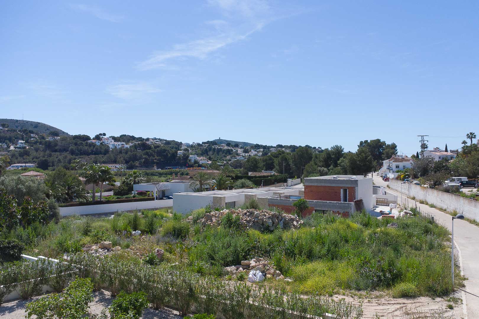 Außenansicht der Villa im Bau, die das moderne strukturelle Design und die Integration in die mediterrane Hügellandschaft von Moraira zeigt.