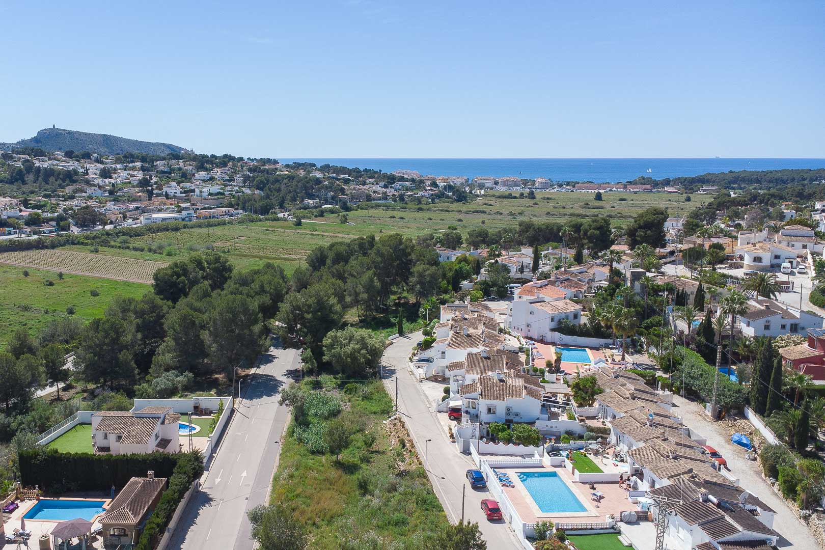 Erhöhter Panoramablick über Moraira mit Sicht auf das Mittelmeer, eingebettet in grüne Landschaften und die typische Wohnarchitektur der Region.