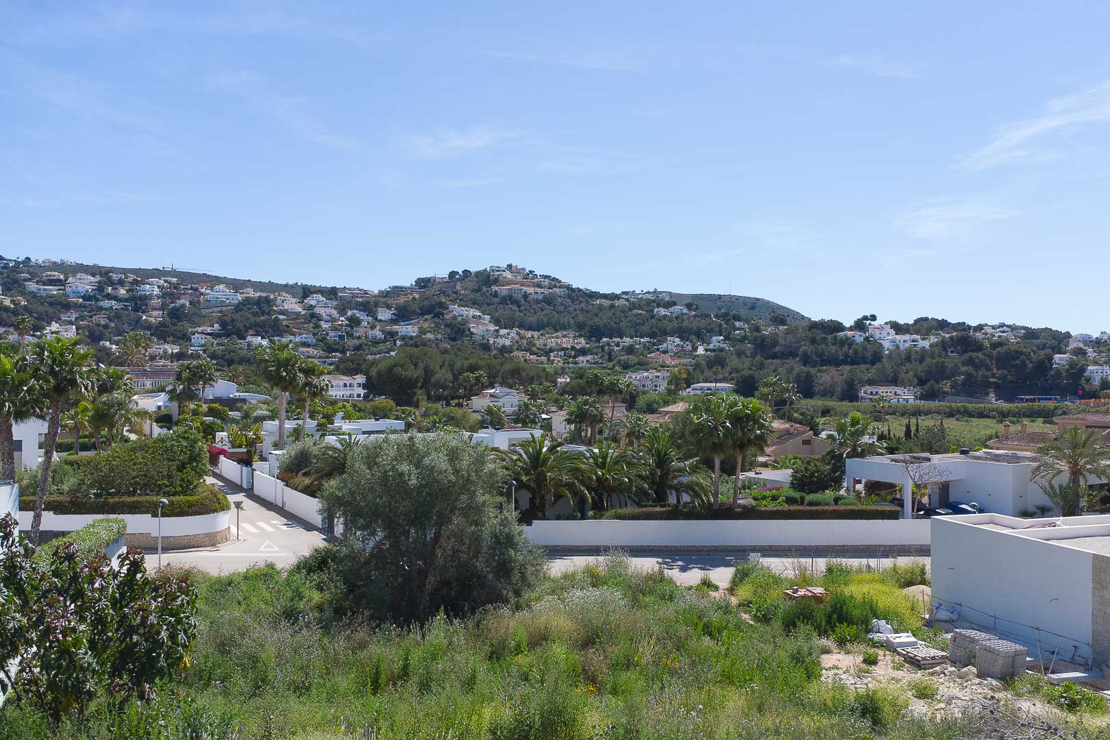 Panoramablick von der Immobilie auf die Wohnlandschaft von Moraira mit grünen Hügeln und mediterraner Architektur unter klarem Himmel.