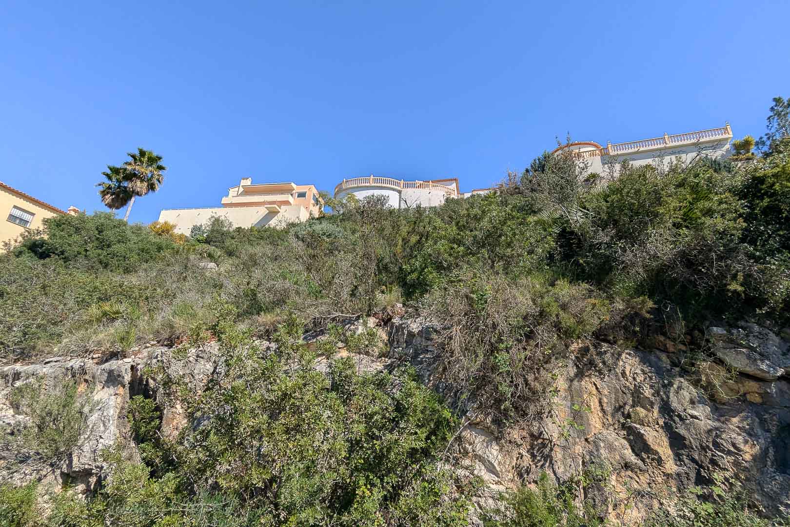 Blick auf die Villa im Bau von der felsigen Basis aus, die ihre Integration in die Landschaft zeigt.