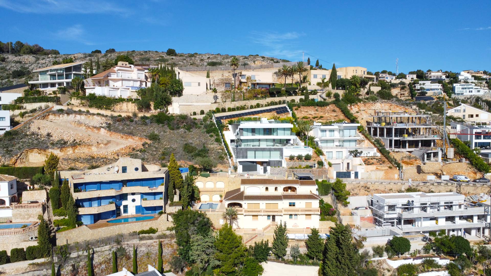 Luftaufnahme der Villa am Hang von La Corona, die die traditionelle dreistöckige Architektur mit Ziegeldächern und in das mediterrane Gelände integrierten Terrassen zeigt.