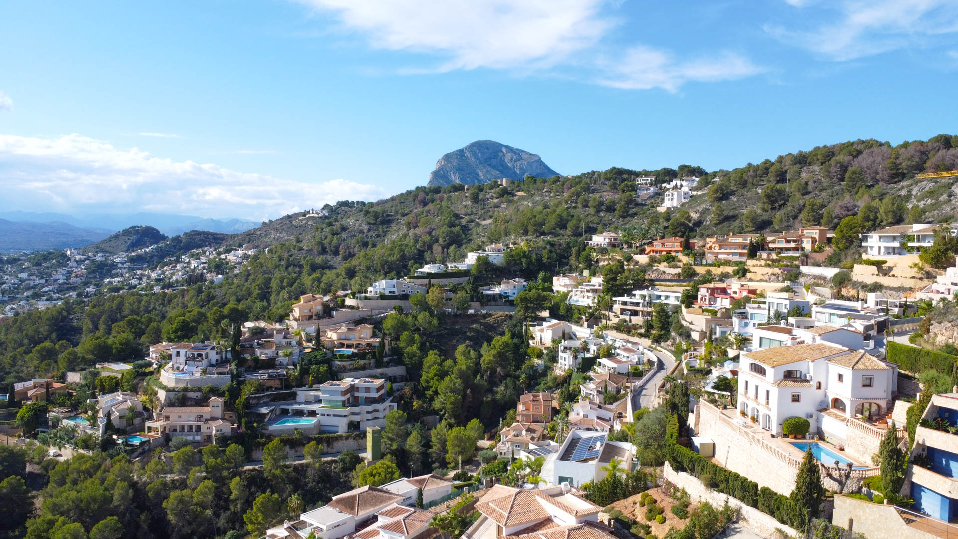 Luftaufnahme des Wohngebiets La Corona in Jávea mit mediterranen Villen am Hang und dem Berg Montgó im Hintergrund.