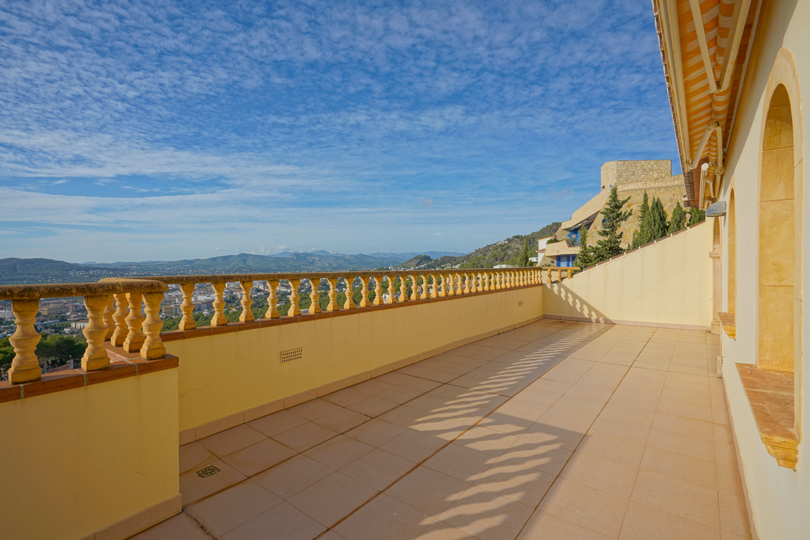 Obere Terrasse mit traditioneller Balustrade und Fliesenboden, die einen weiten Panoramablick über das Tal von Jávea und die angrenzende Berglandschaft bietet.