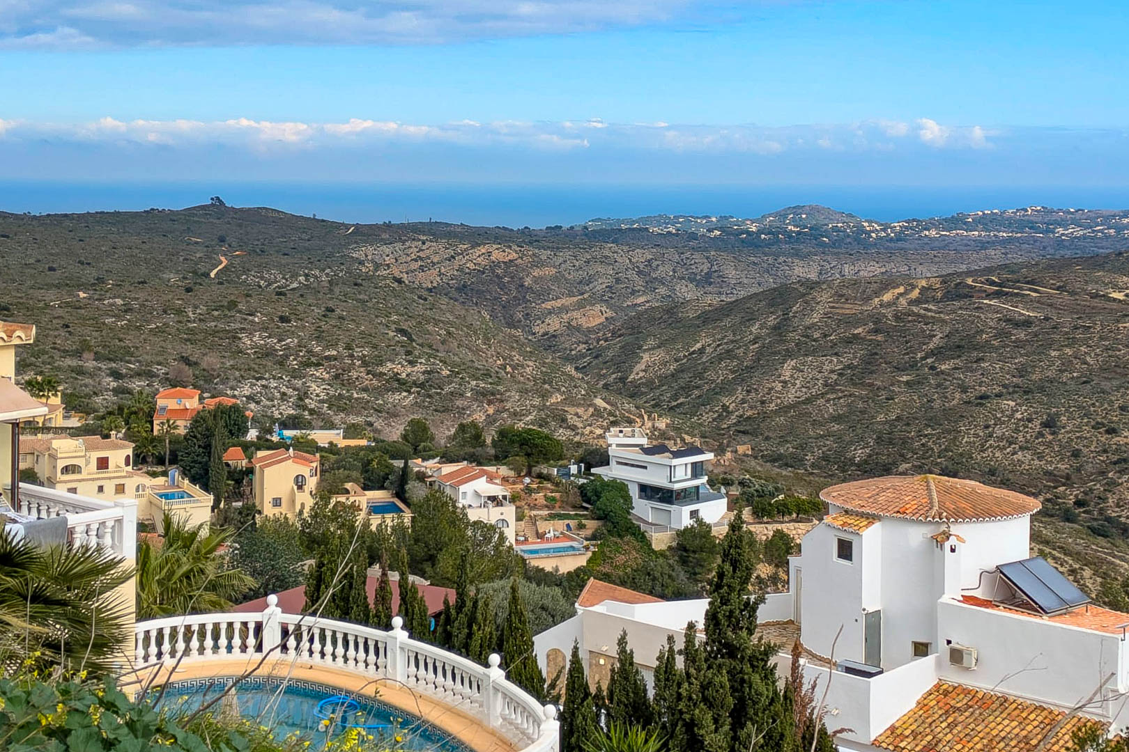 Panoramablick von Cumbre del Sol auf das Mittelmeer, der die bergige Küstenlandschaft und die in die Hänge gebetteten Villen von Benitachell zeigt.
