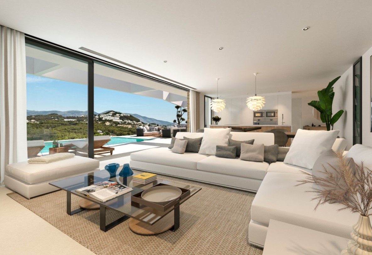 Offener Wohnraum mit weißem Ecksofa und Glastisch, der durch große Fensterfronten nahtlos in die Poolterrasse mit Bergblick übergeht.