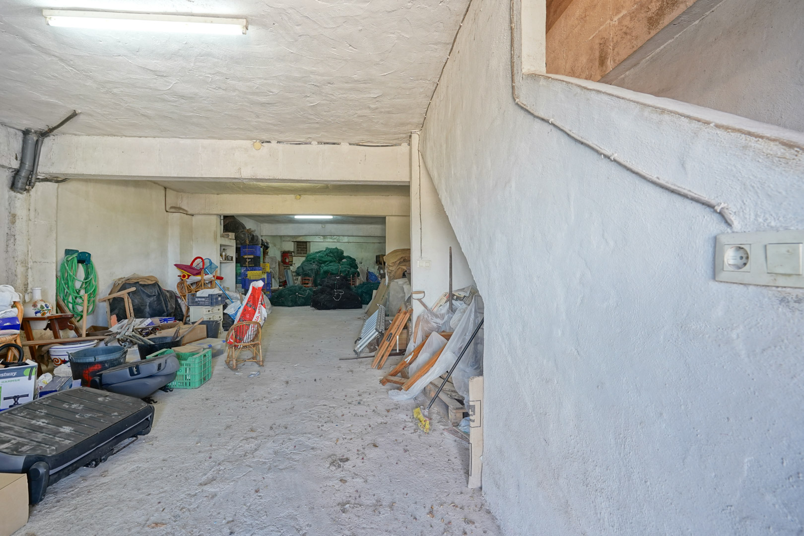 Große Garage im Untergeschoss mit Betonboden und verputzten Wänden. Eine integrierte Seitentreppe bietet direkten Zugang zu den darüber liegenden Wohnräumen.