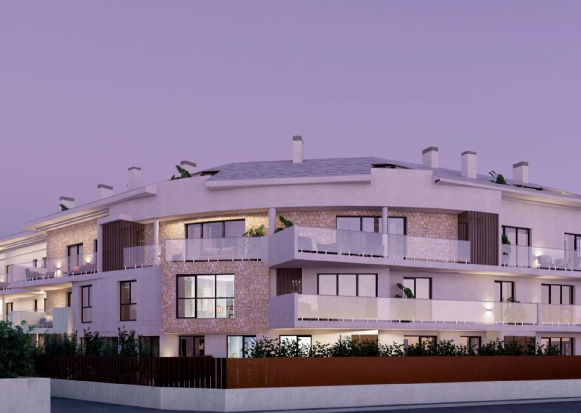 Außenfassade der Wohnanlage in Javea mit Natursteinverkleidung, großzügigen Terrassen mit Glasgeländern und integrierter Außenbeleuchtung in der Abenddämmerung.