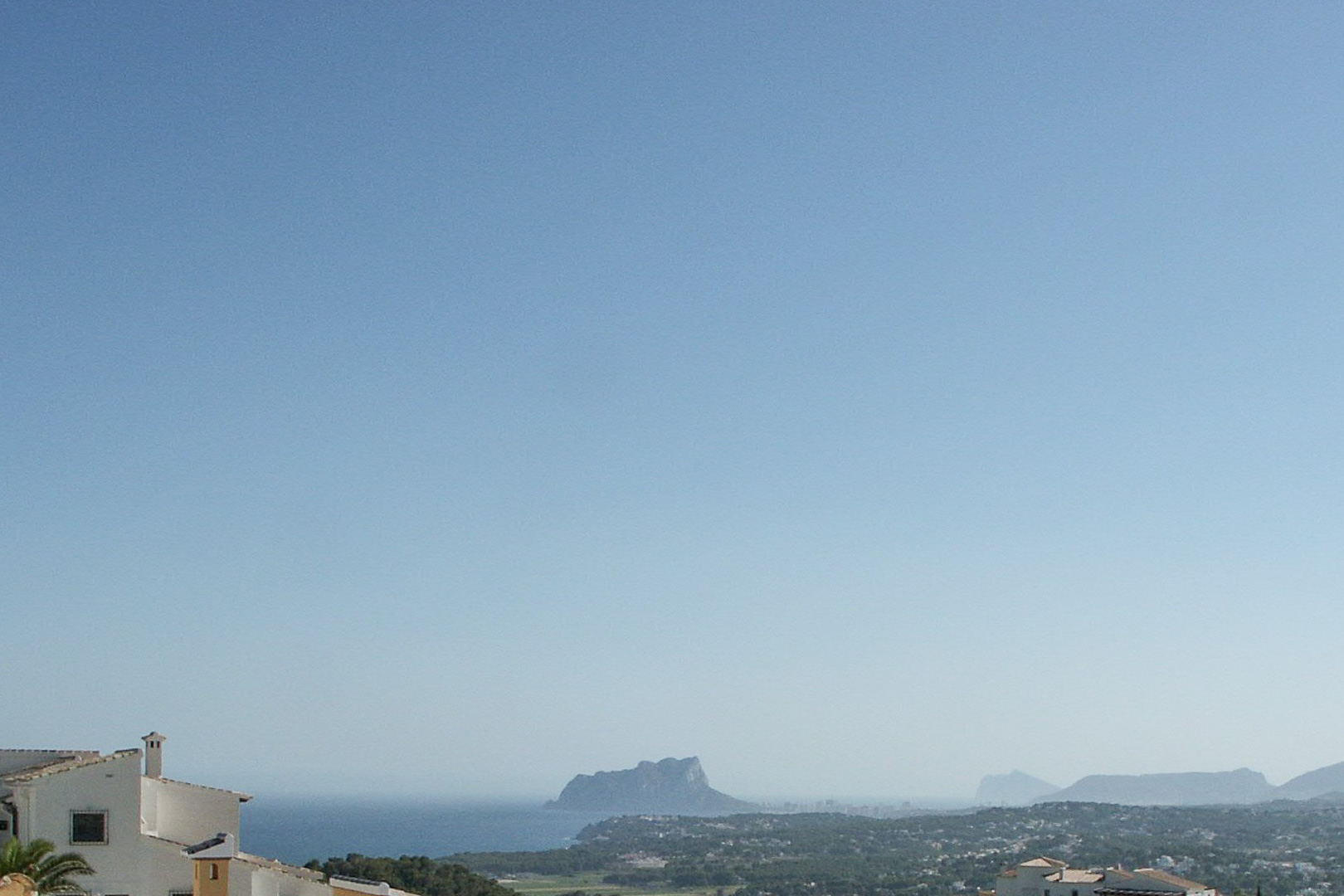 Panoramablick vom erhöhten Grundstück auf die Küste von Calpe mit der Silhouette des Peñón de Ifach und dem Mittelmeer.