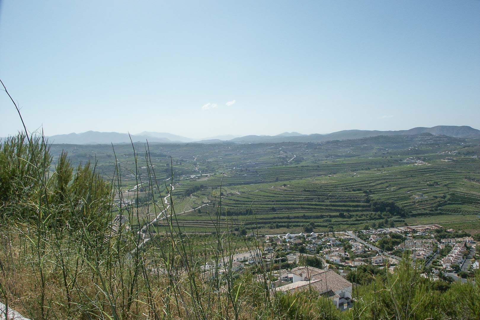 Panoramablick vom erhöhten Grundstück in Paichi auf terrassierte Felder und die umliegende Berglandschaft unter klarem Himmel.