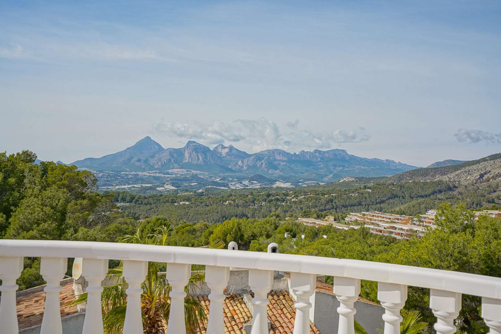 Terrasse mit weißer Balustrade und weitem Panoramablick auf die Gebirgsketten des Puig Campana und der Sierra Aitana.