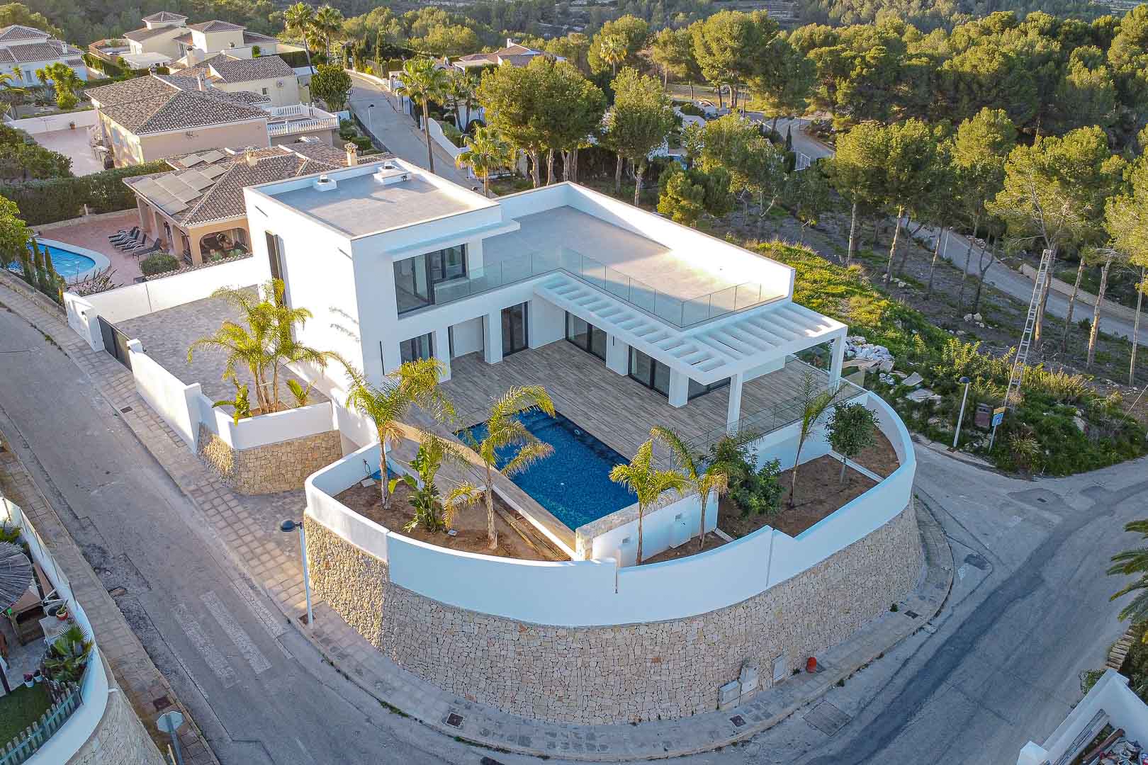 Luftaufnahme der modernen Villa mit blauem Pool, Pergola-Terrasse und mediterranem Garten in Benimeit, Moraira.