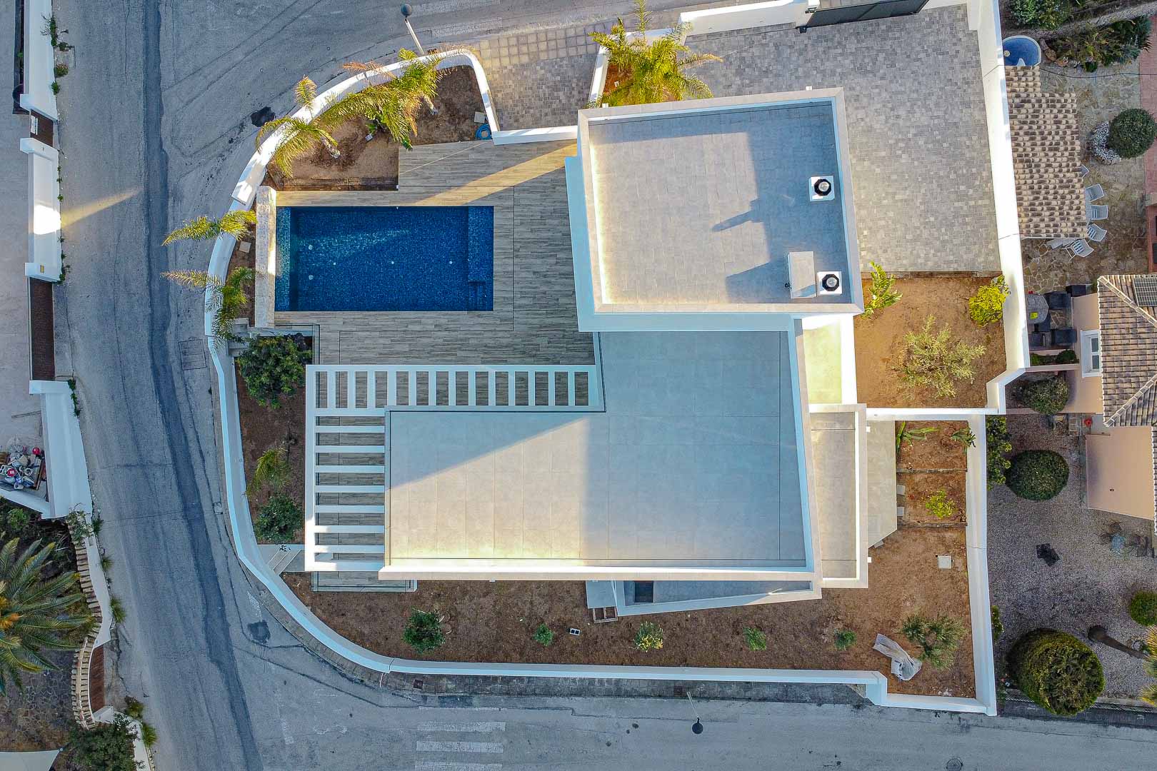 Luftaufnahme einer modernen Villa in Benimeit mit blauem Pool und grauen Fliesenterrassen.