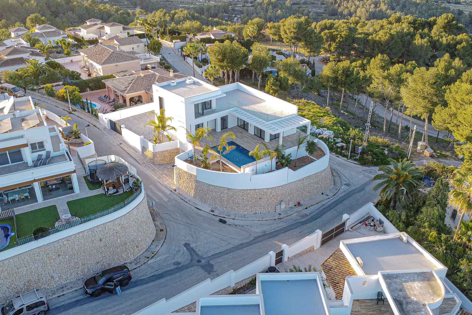Luftaufnahme einer modernen Villa mit blauem Pool, umgeben von Steinmauer und Grün in Benimeit, Moraira.