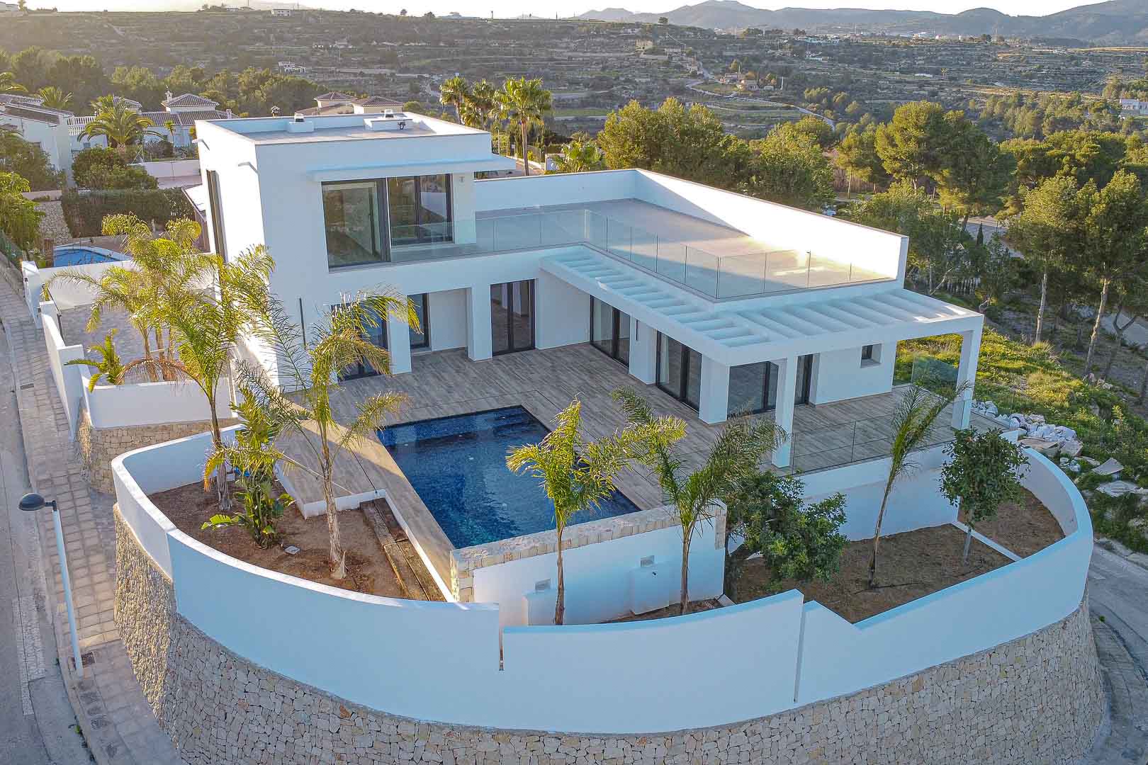 Luftaufnahme einer modernen Villa mit blauem Pool und weißen Mauern mit Steindetails in Benimeit, Moraira.