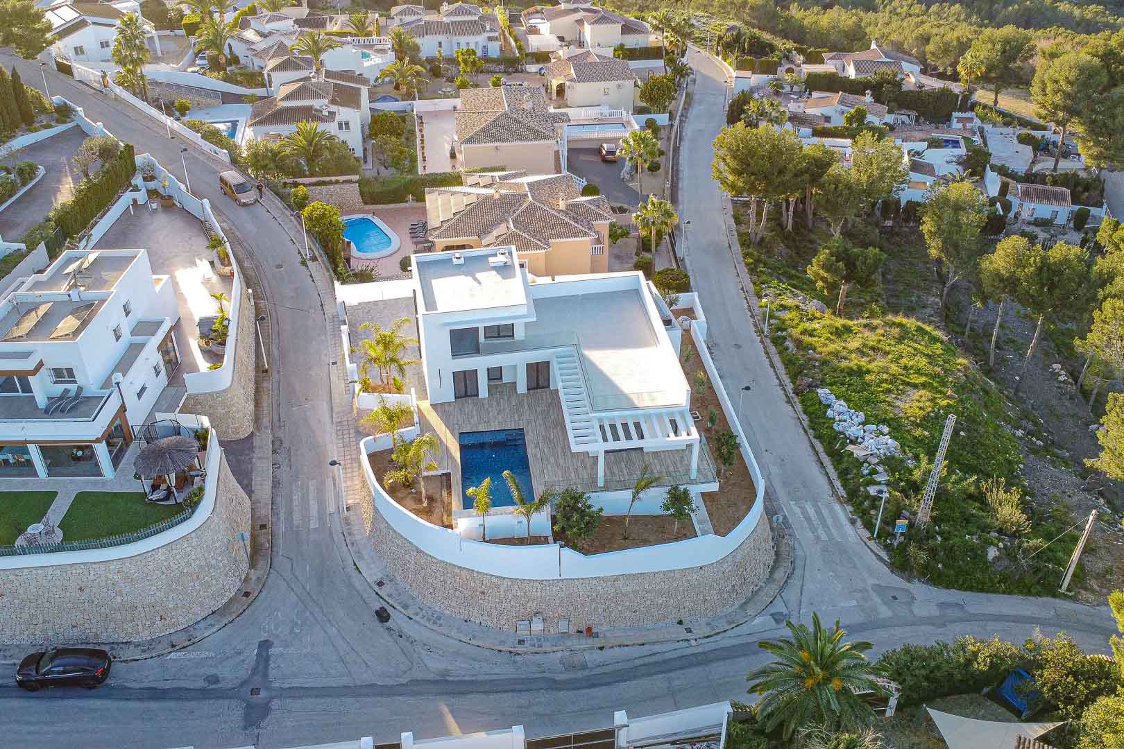 Luftaufnahme einer modernen Villa mit Pool in Benimeit, Moraira. Minimalistisches Design, Terrassen und mediterraner Garten.