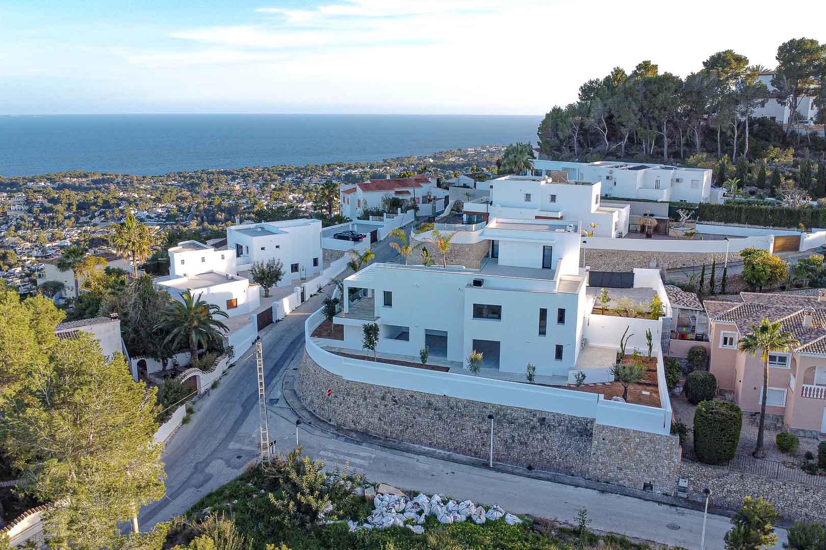 Luftaufnahme einer modernen weißen Villa mit Steinmauern und Meerblick in Benimeit, Moraira.