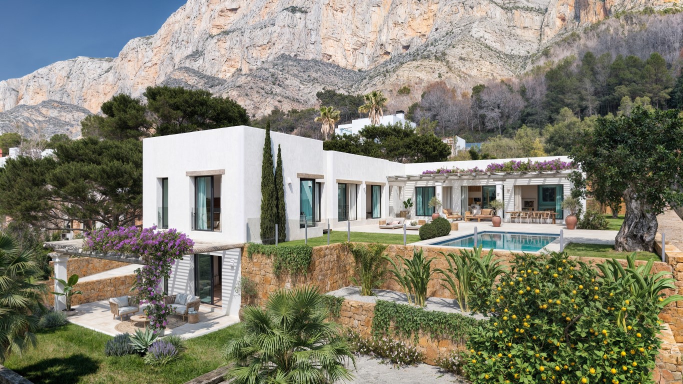 Außenansicht der Villa mit weißen Fassaden, privatem Pool und Natursteinmauern vor der markanten Kulisse des Montgó-Massivs in Jávea.