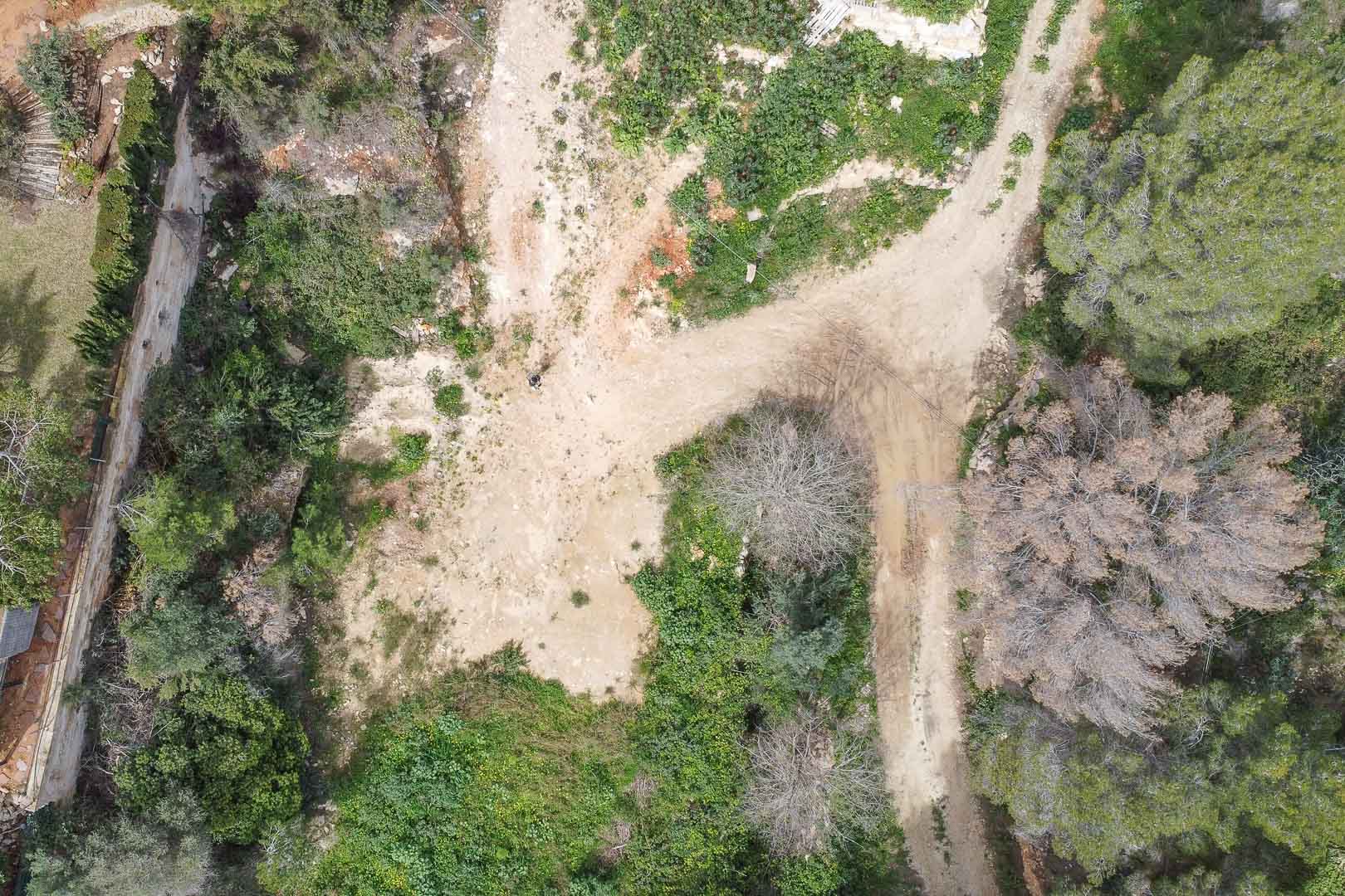 Luftaufnahme des Baugrundstücks in La Corona mit natürlichem Gelände, mediterraner Vegetation und Zufahrtswegen vor Beginn des maßgeschneiderten Villenprojekts.