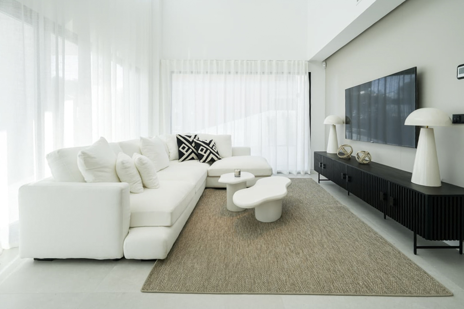 Helles Wohnzimmer mit modularem weißen Sofa, modernem Beistelltisch und Juteteppich.