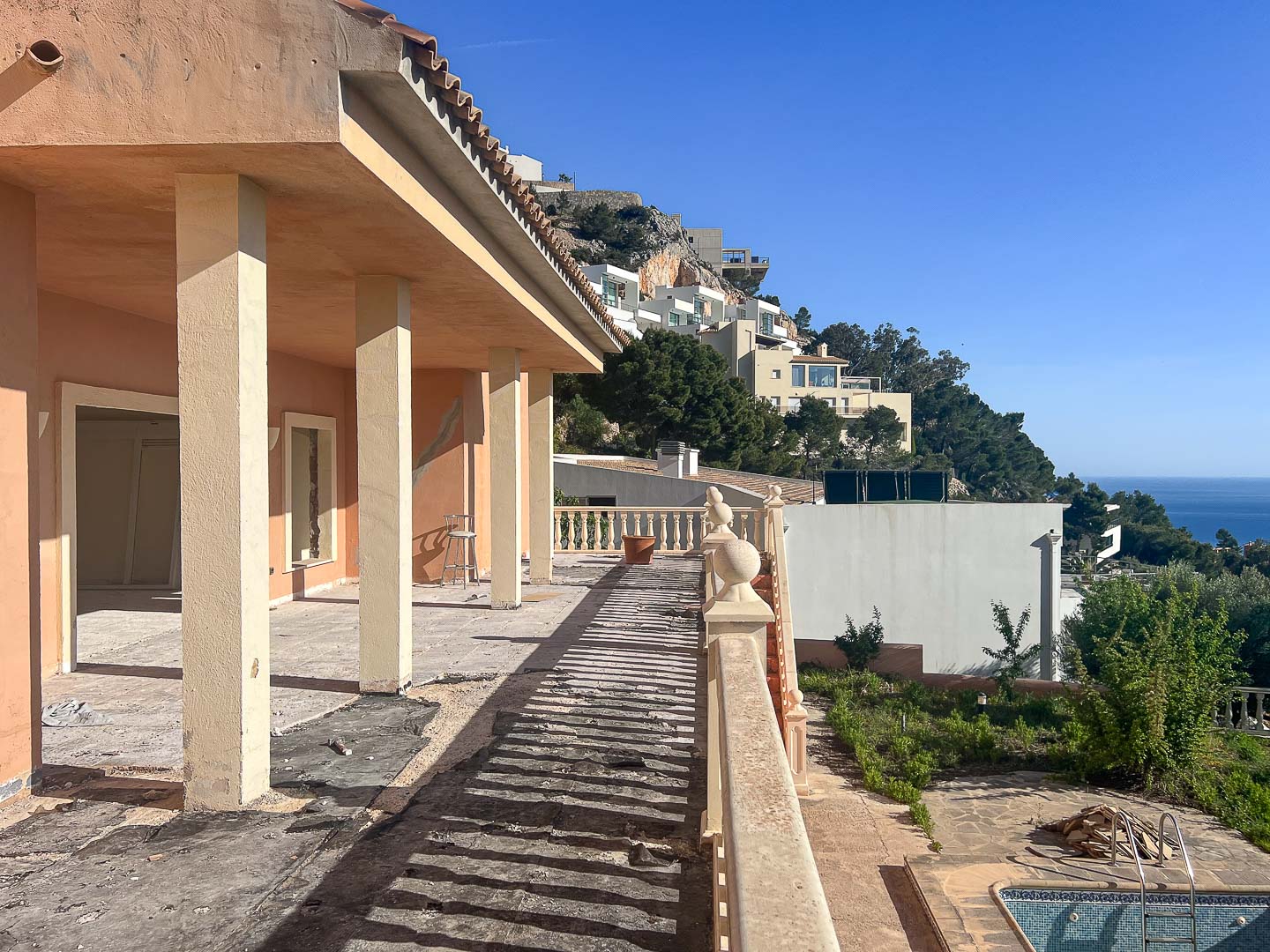 Außen-Terrasse in Renovierung mit strukturellen Säulen, klassischer Balustrade und Panoramablick auf die Hügel von Altea und das Mittelmeer.