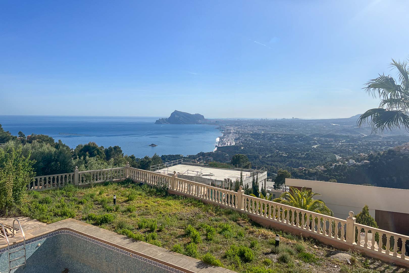 Panoramablick auf das Mittelmeer und den Peñón de Ifach vom Außenbereich mit Steinbalustrade und Gartenanlage.