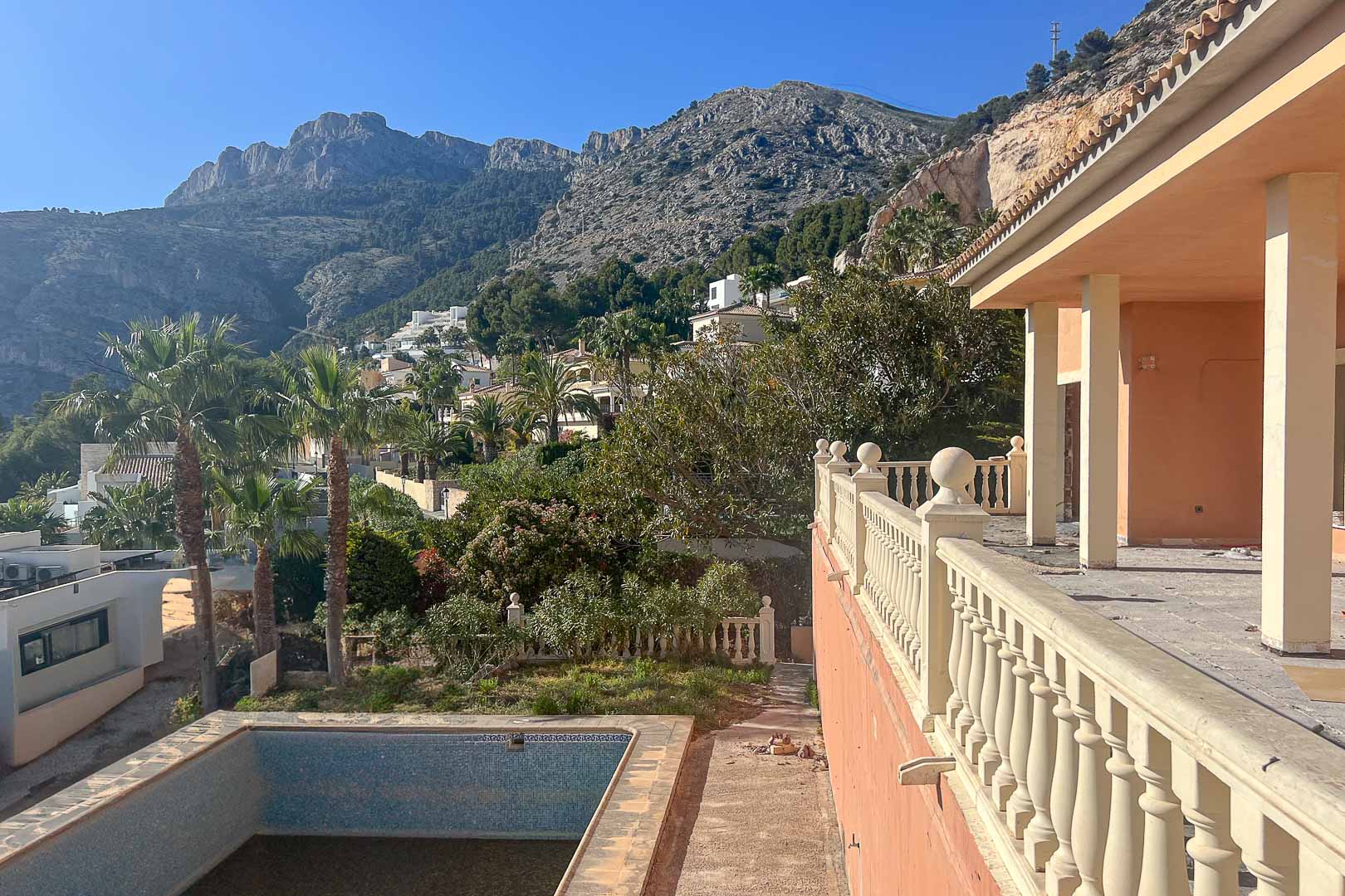 Terrasse mit klassischer Balustrade und Blick auf das Sierra de Bernia-Gebirge. Außenbereich mit privatem Pool und üppiger mediterraner Bepflanzung.