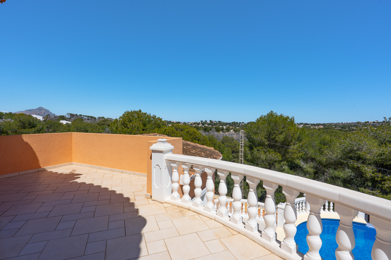 Obere Terrasse mit Keramikfliesen und klassischer weißer Balustrade, mit Blick auf den privaten Pool und die umliegende Landschaft.