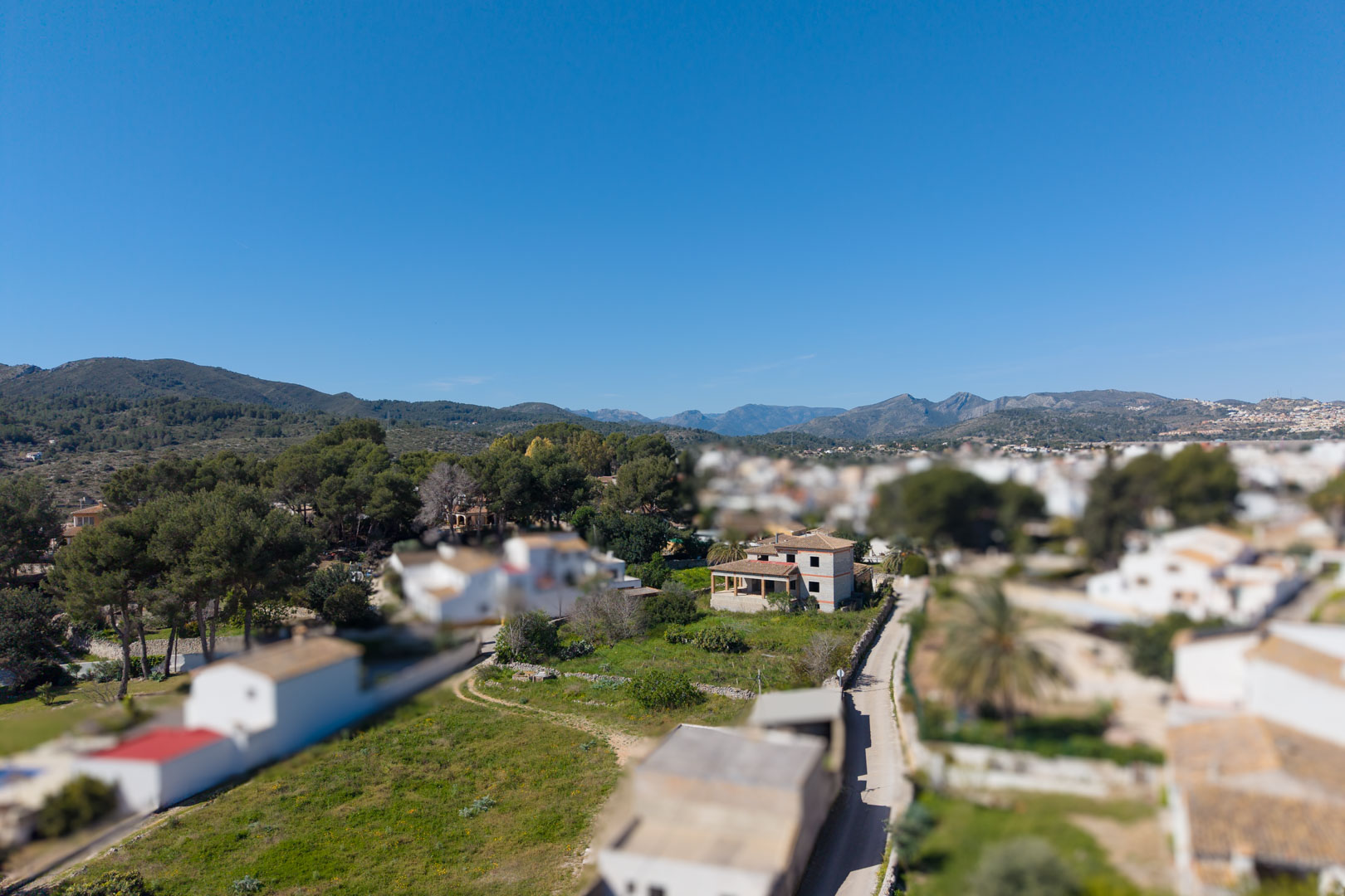 Luftaufnahme des zweistöckigen Rohbaus auf einem großen Gartengrundstück in Gata de Gorgos, mit Blick auf die markante Bergkulisse der Region.