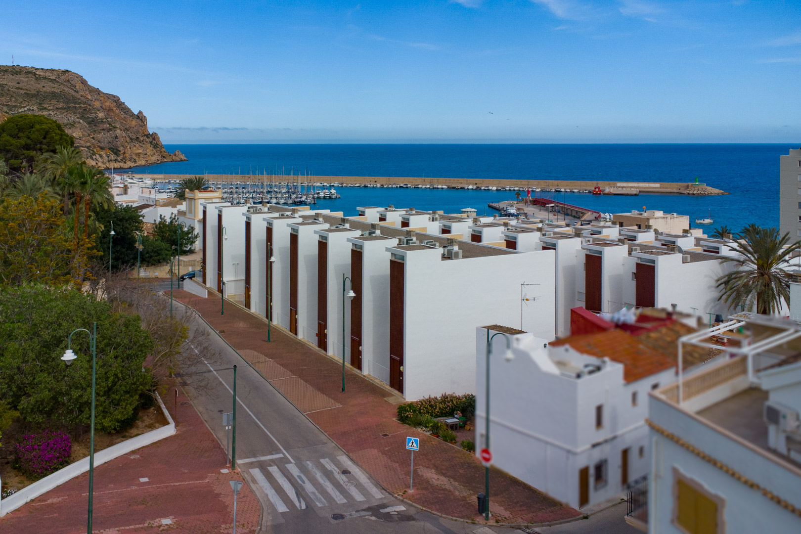Panoramablick auf den Hafen von Jávea und das Mittelmeer mit moderner weißer Architektur, Küstenstraßen und der markanten felsigen Küstenlinie.