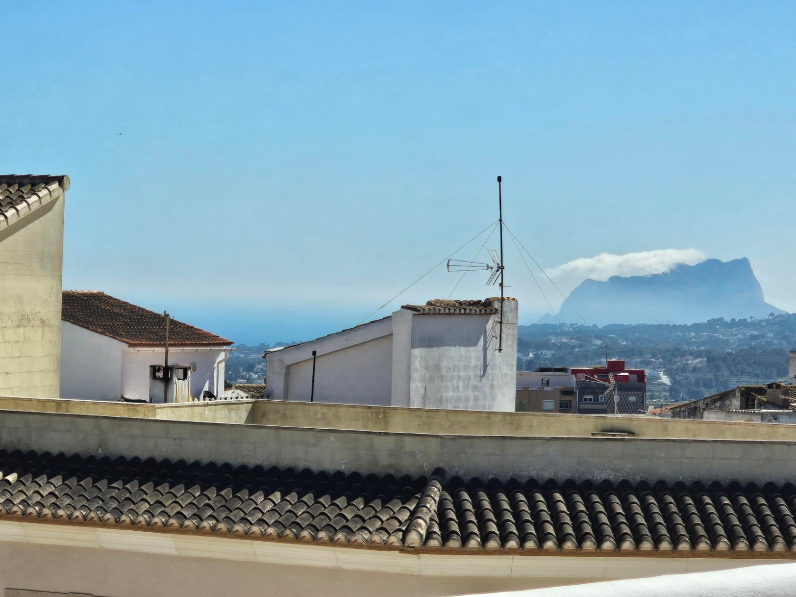 Panoramablick von der oberen Terrasse über die Dächer der Stadt, das Tal und das Mittelmeer, mit dem markanten Peñón de Ifach am Horizont.