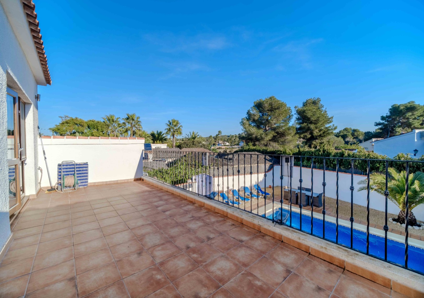 Obere Terrasse mit Terrakotta-Fliesen und schwarzem Eisen-Geländer, mit Blick auf den privaten Pool und die umliegende mediterrane Landschaft.