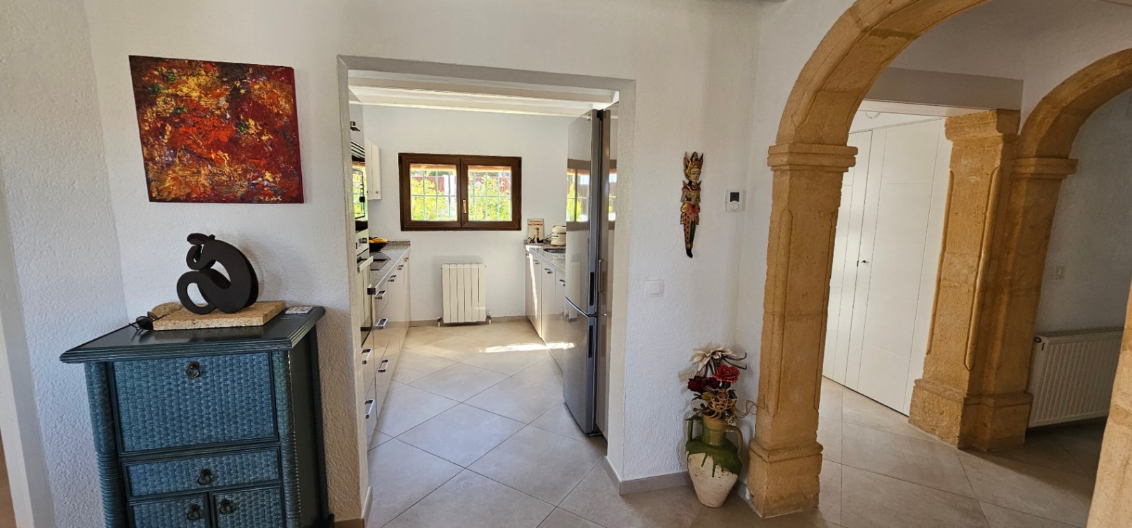 Eingangsbereich mit traditionellen Tosca-Steinbögen und Blick in die helle, separate Küche mit modernen Geräten und Zentralheizung.