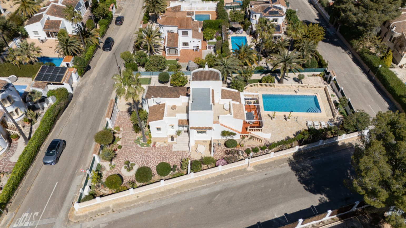Luftaufnahme der Villa auf einem Eckgrundstück mit privatem Pool, weitläufigen gepflasterten Terrassen und gepflegten mediterranen Gärten in Pinosol.